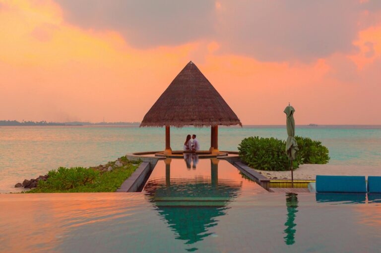 couple under hut beside sea and infinity pool